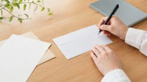 私書箱の宛名の書き方を確認しながら封筒に記入する様子