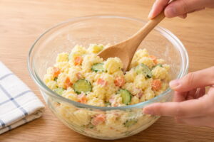 水っぽいポテトサラダをボウルで混ぜて直している様子
