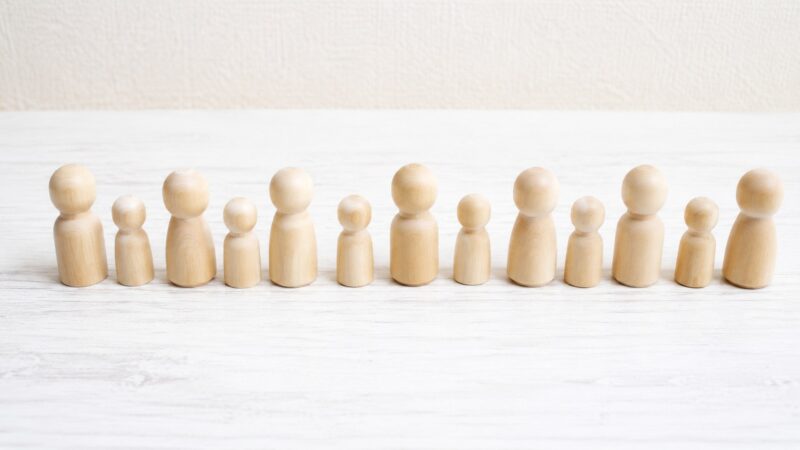 大所帯と大世帯の違いを表す大人数の木製人形