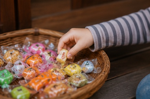 お月見泥棒で玄関先のかごからお菓子を取る子どもの手元