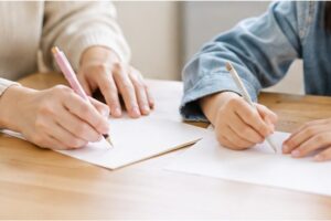 産休に入る担任の先生へのメッセージを書く親子の手元