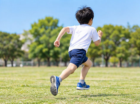 小学生が速く走るコツを意識して芝生の上を走る後ろ姿